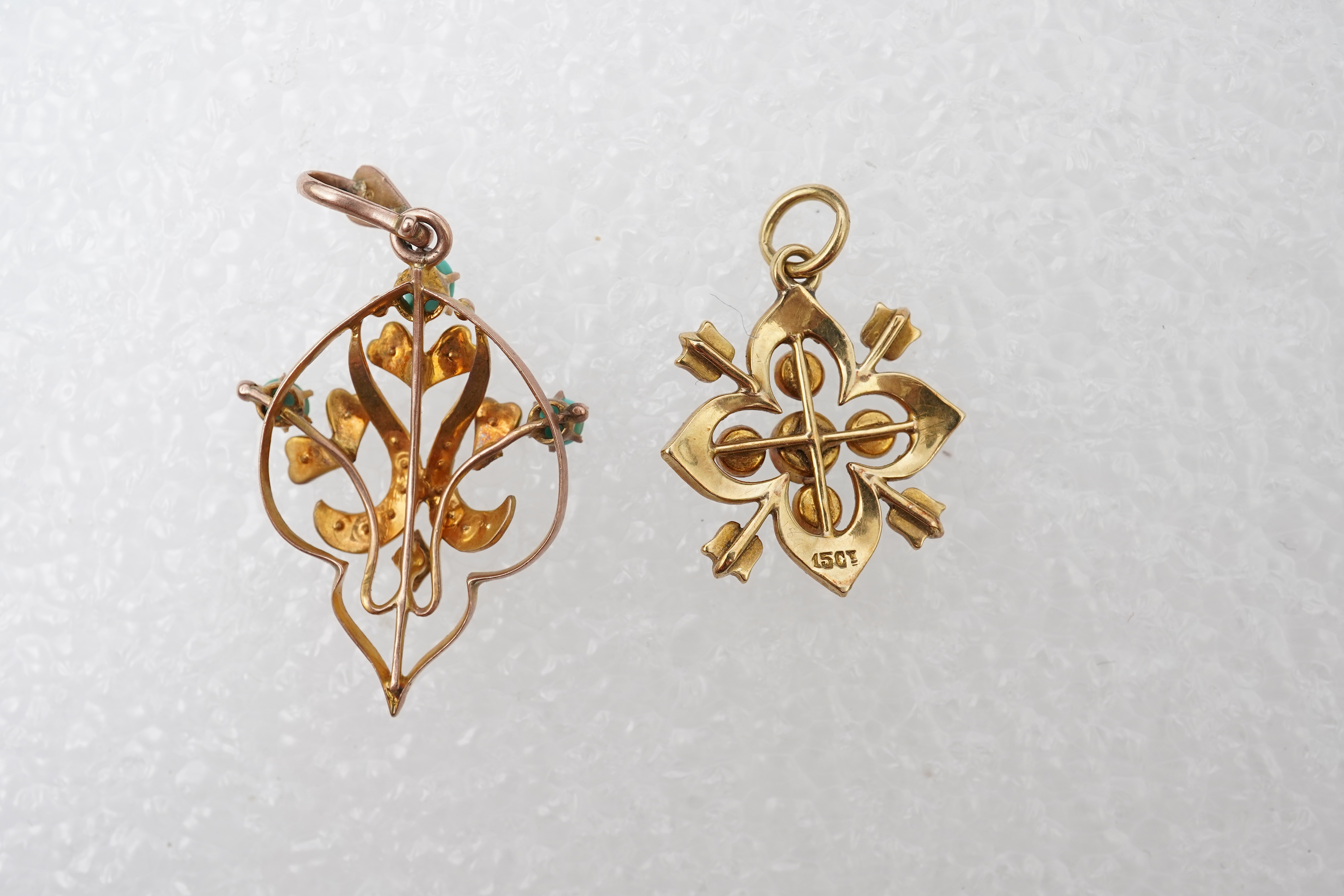 Two Edwardian turquoise and seed pearl pendants, each of foliate design, set with turquoise cabochons and seed pearls, mounted in gold, longest 3.7cm, smaller stamped 15CT, combined gross weight approximately 4 grams